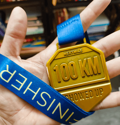A 100 km finisher medal held in one hand