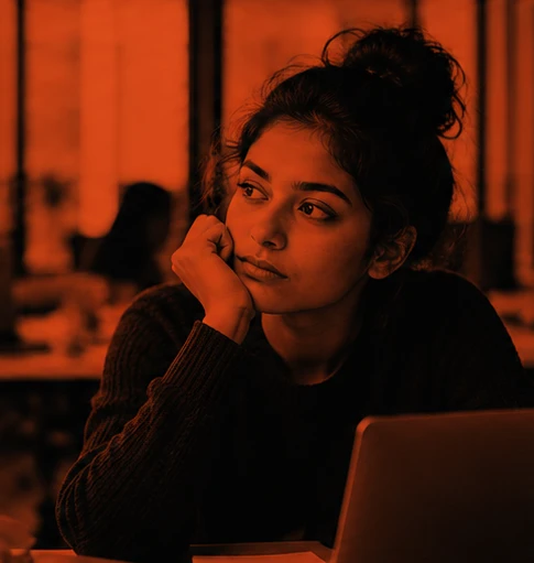 Anuprba at a café table, chin in hand, looking away from her laptop